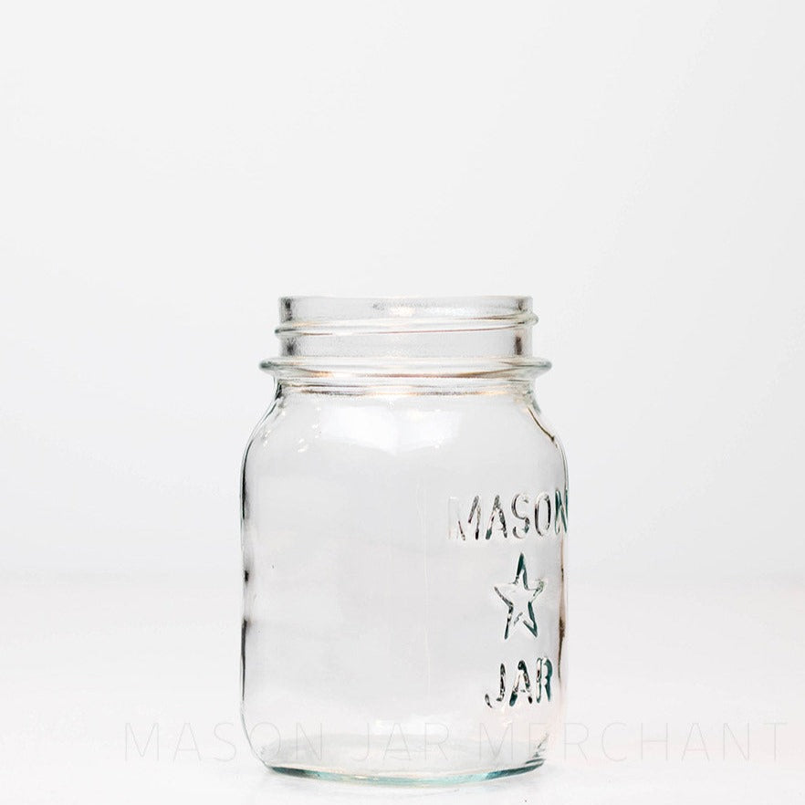 side view of a Regular mouth pint mason jar with mason star logo on a white background