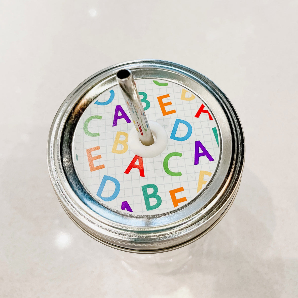 top photo of mason jar lid with colorful alphabets