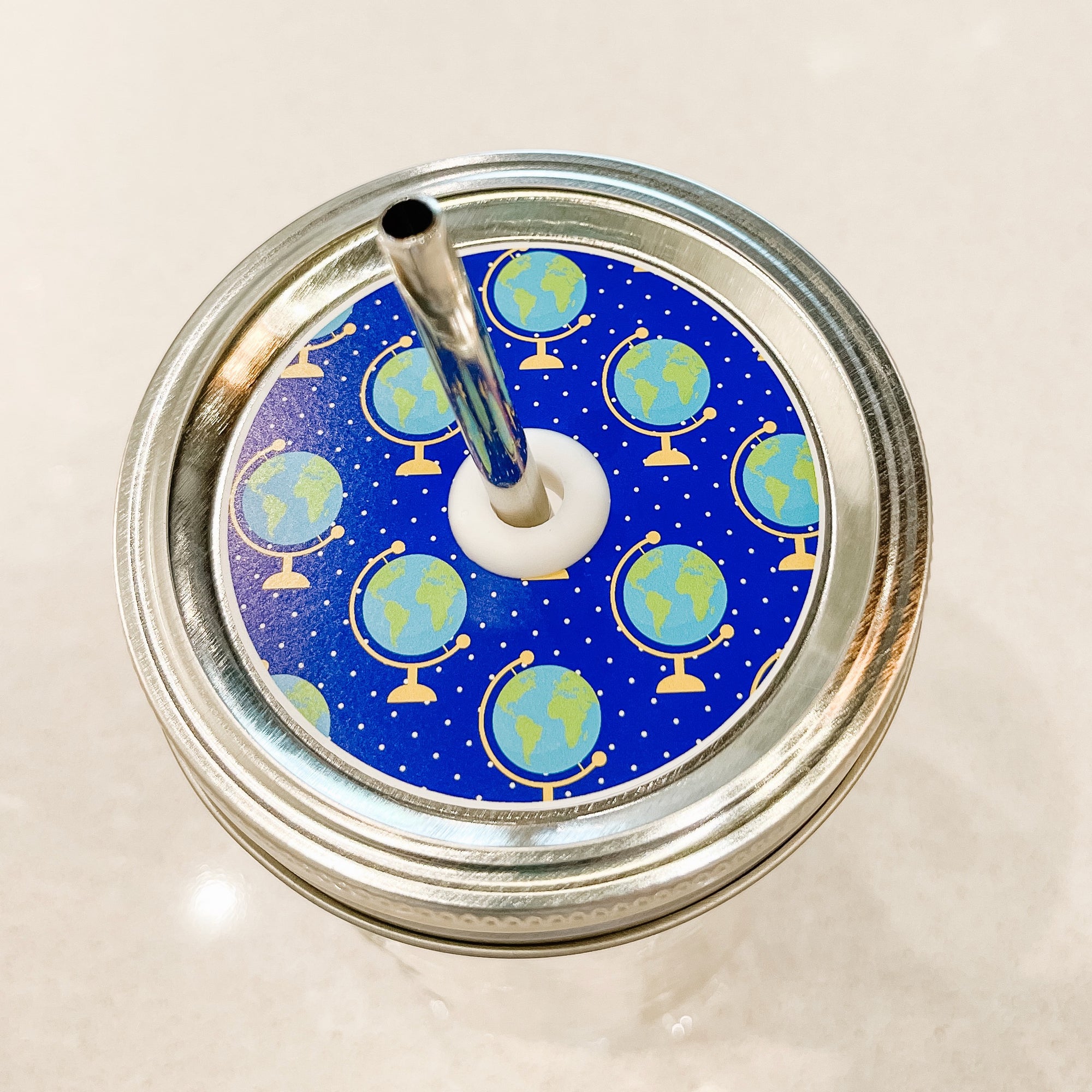 top photo of mason jar lid with globes and a blue background