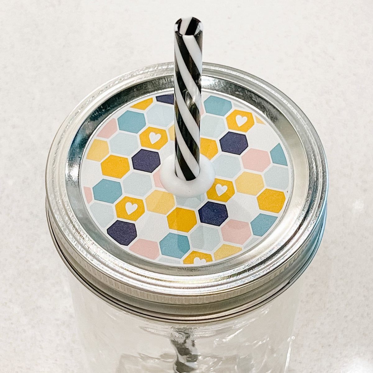 top photo of mason jar lid with a blue, pink, yellow and white honeycomb