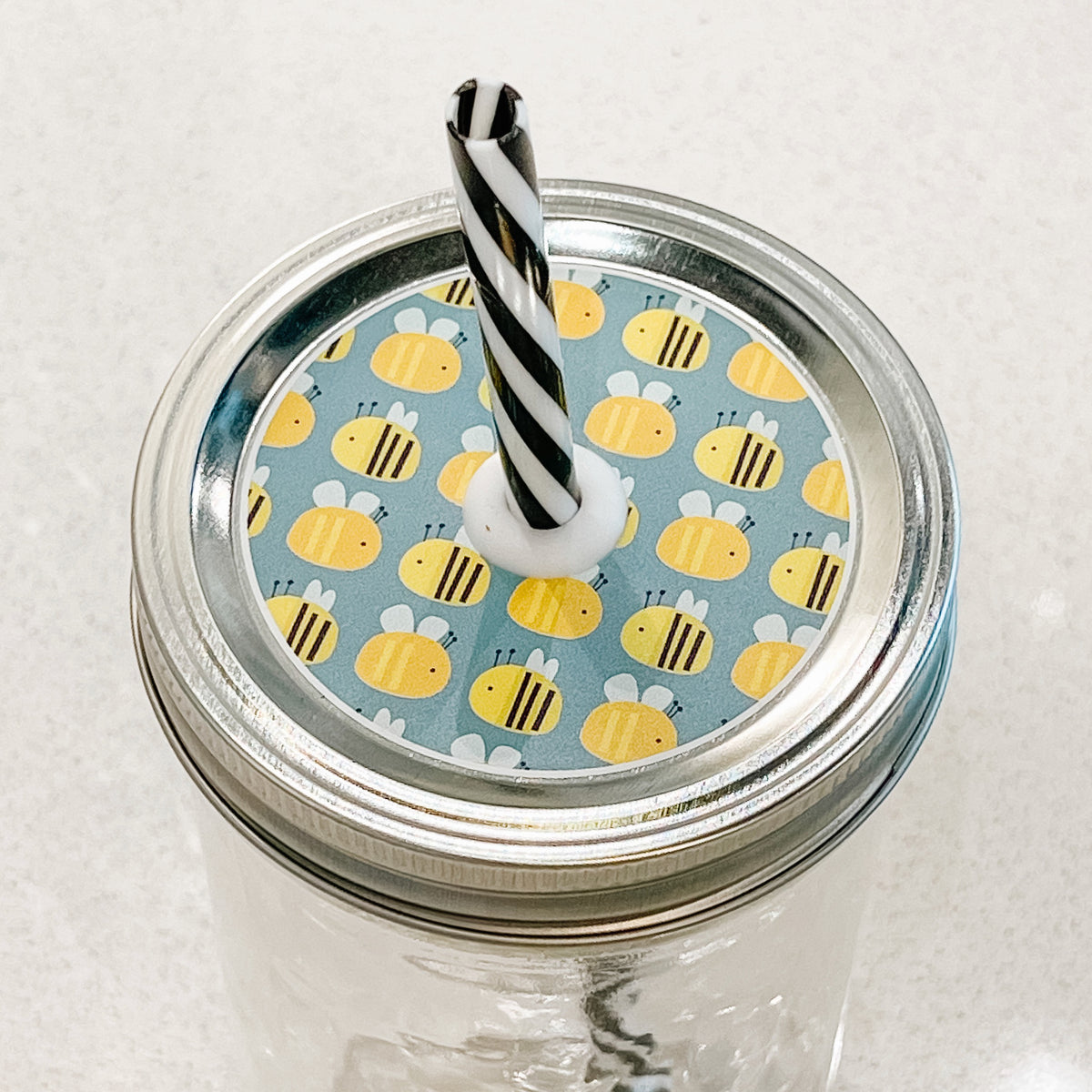 top photo of mason jar lid with bees and a light blue background 