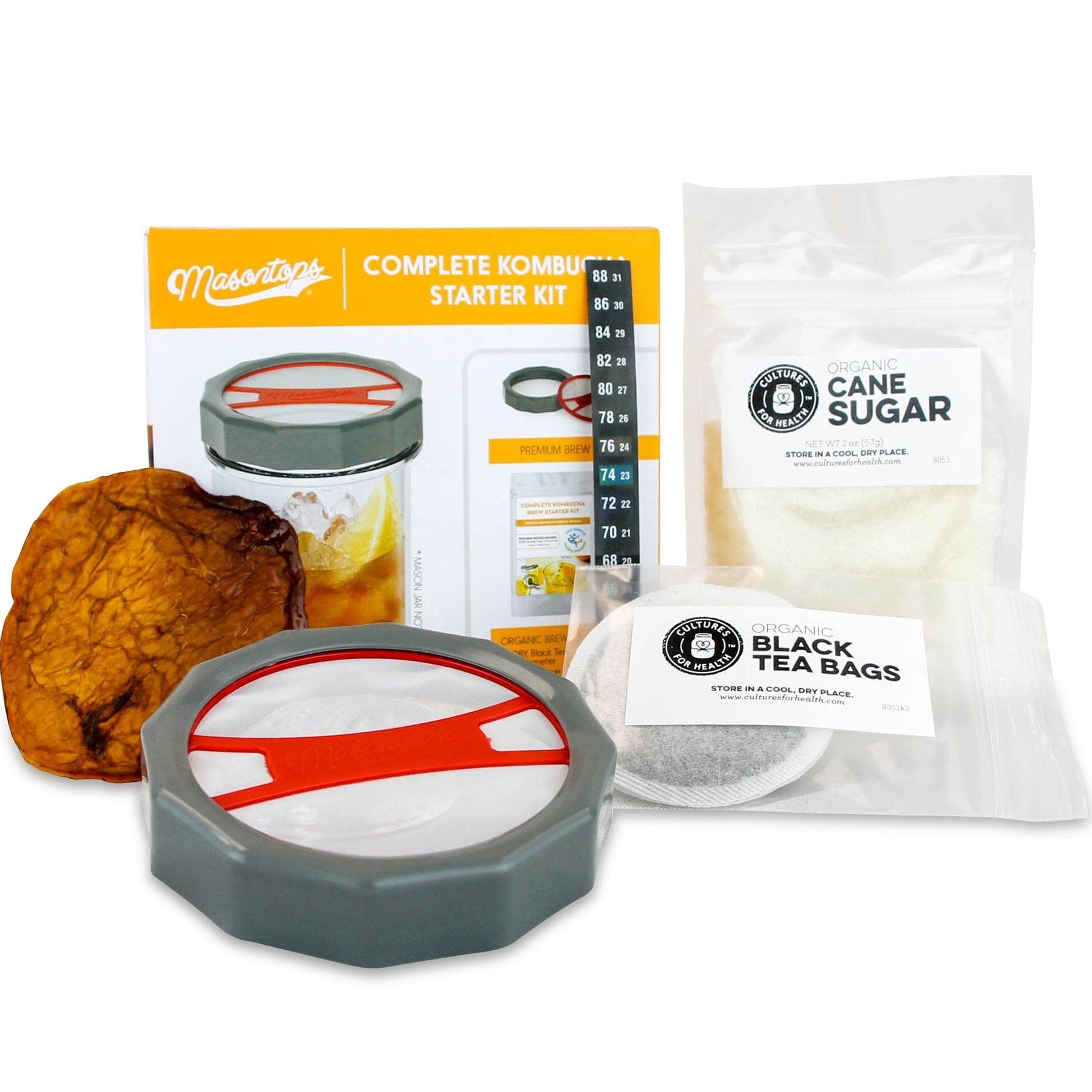A photo of a complete kombucha kit that includes organic cane sugar, organic black tea bags, and a jar or a glass with a lid.