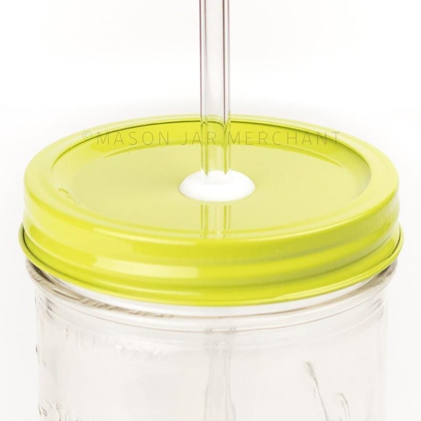 Close-up of a 24 oz mason jar with a chartreuse custom painted lid with a white silicone grommet and a glass straw, against a white background