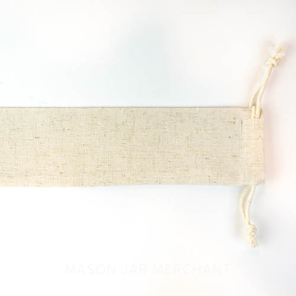 close up of a beige reusable draw string straw bag on a white background
