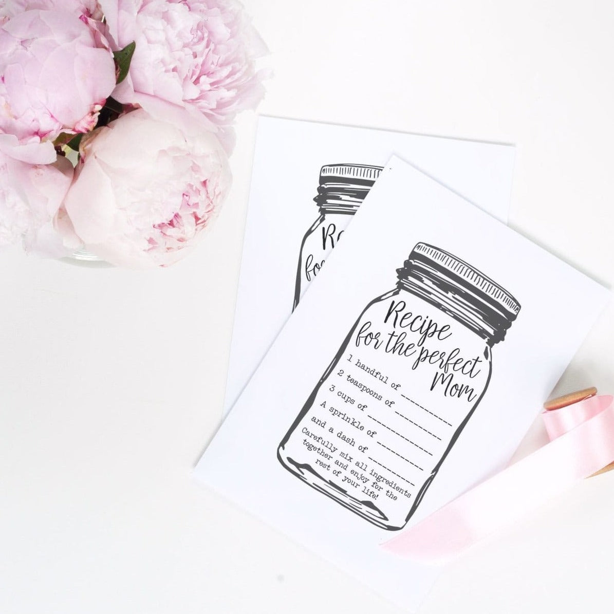 two pieces of paper with a black mason jar outline on it and a &quot;recipe for the perfect mom&quot; on the inside. It sits on a white background with pink peony flowers on the side
