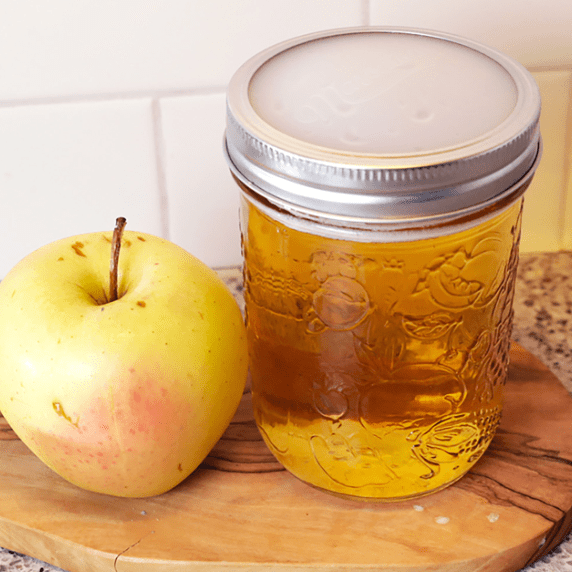 A mason jar with silicone seals beside an apple