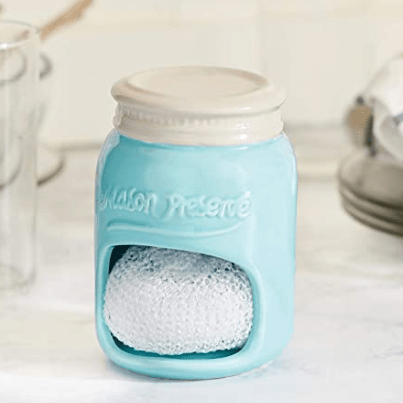 Close up of a glass blue and grey mason jar sponge holder on a kitchen counter