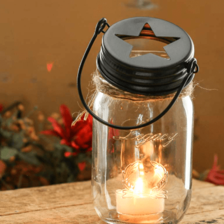 Rustic Star Cutout Hanging Mason Jar Lid on a mason jar with candle inside on top of a table