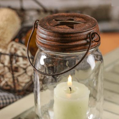 Rustic Star Cutout Hanging Mason Jar Lid on a mason jar with candle inside on top of a table