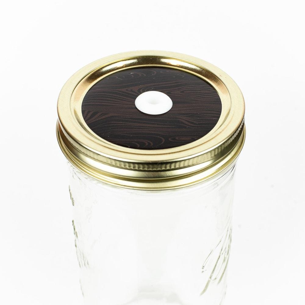 Dark wood patterned mason jar straw lid against a white background.