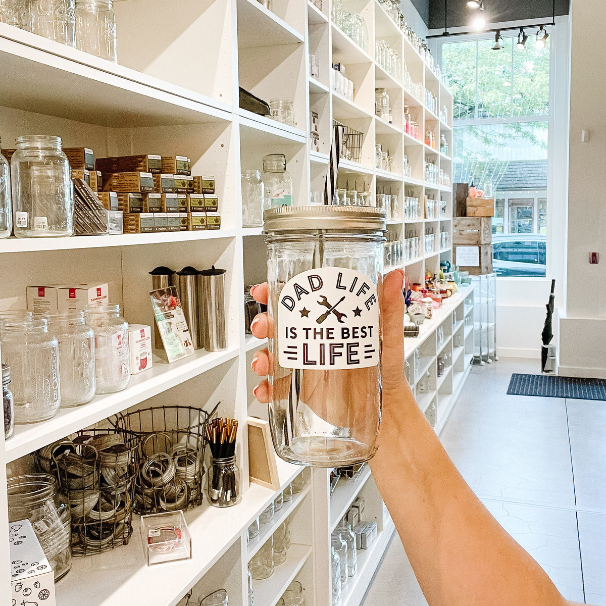 hand holding a mason jar tumbler that says "DAD LIFE IS THE BEST LIFE" with a wrench and screwdriver making an x in the middle