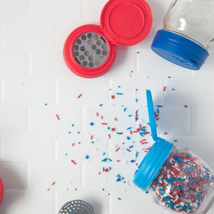 Two mason jar with Jarware flip cap lids showing off the shaker inserts with sprinkles against a white background