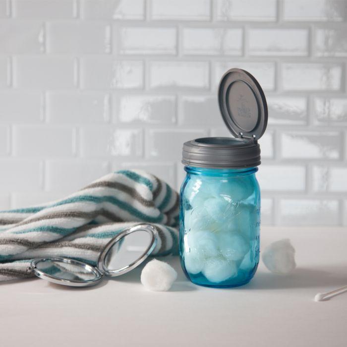 Grey reCAP flip cap or mason jar flip top lid on a blue transparent mason jar with cotton balls inside.