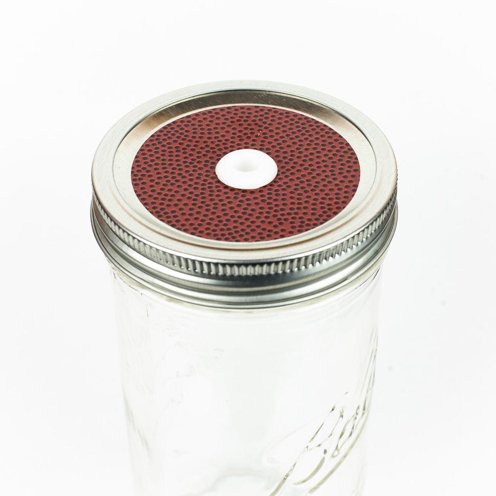 Silver lid with a football patterned mason jar straw lid against a white background.