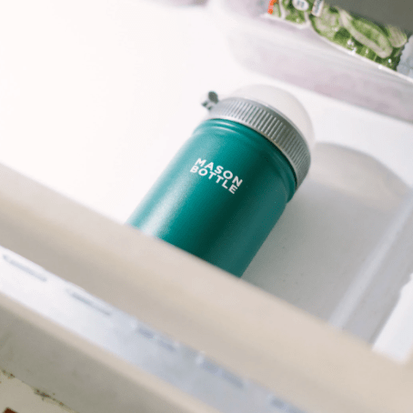 Photo of a stainless steel mason bottle with straw top in forest green placed in a drawer.