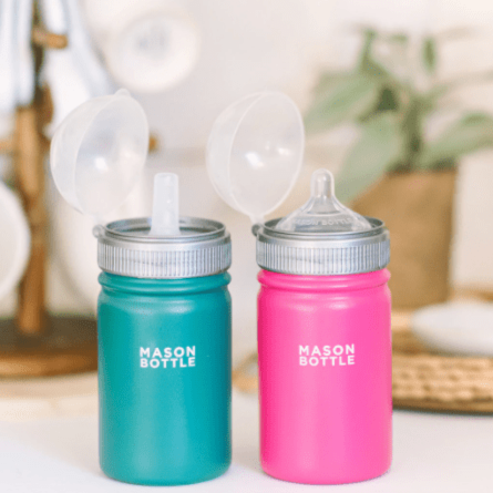 Photo of stainless steel mason bottle with straw top in forest green and pink. Photographed against a white countertop.